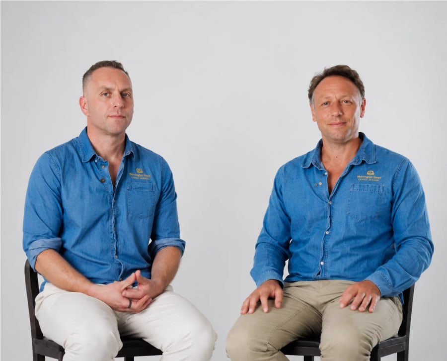 The two founders of Mornington Green seated side by side in branded denim shirts.
