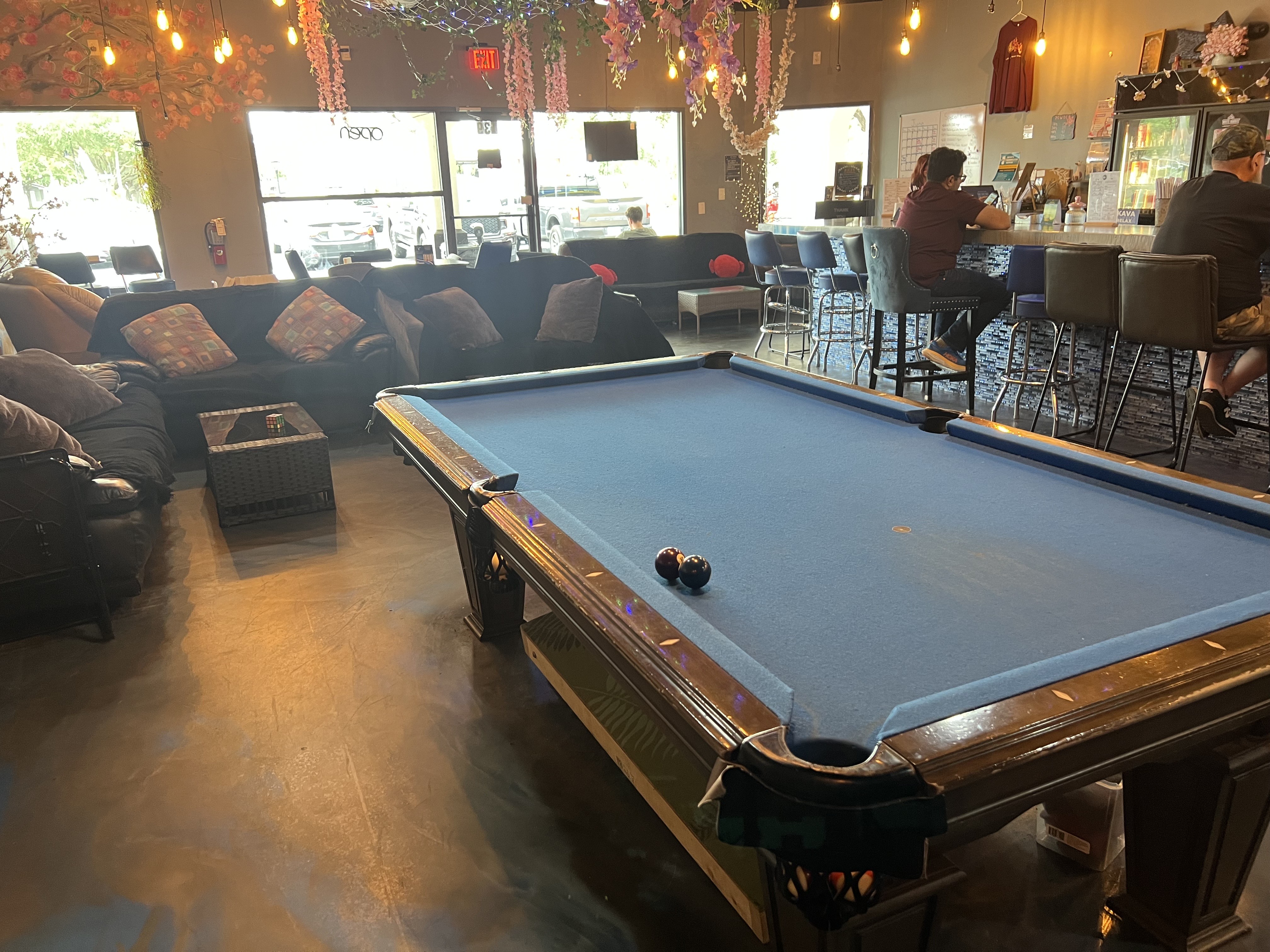 Inside Lei Kava — pool, chess, plant wall, warm lighting