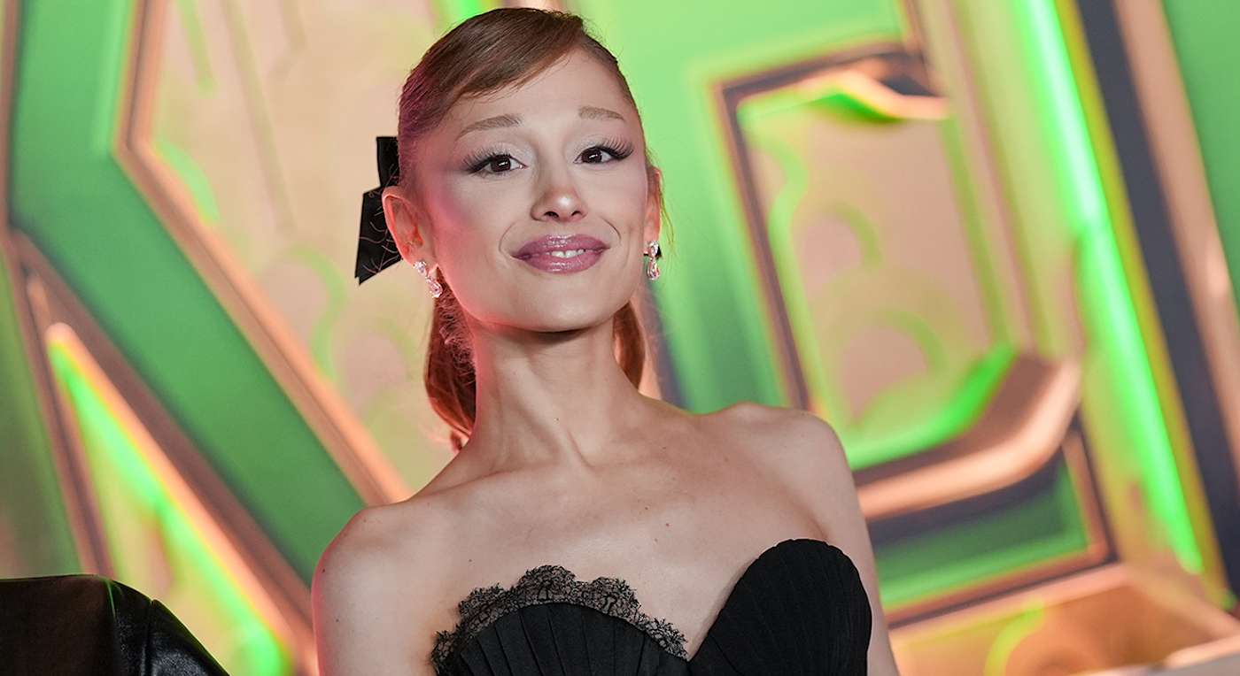 Sängerin Ariana Grande in schwarzem Kleid vor Graffiti-Fassade
