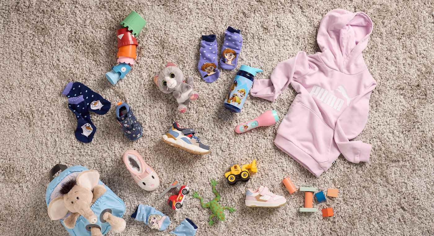 Kollektion einzelner Kinder-Kleidungsstücke & Accessoires auf einem Teppich