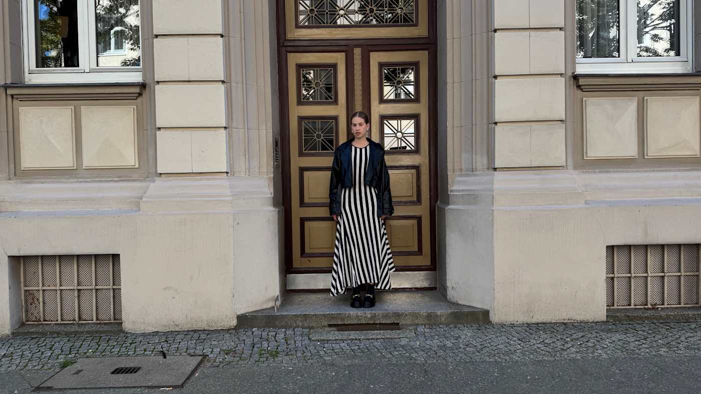 Frau in herbstlichem Kleid im Zebra-Muster steht in Hauseingang