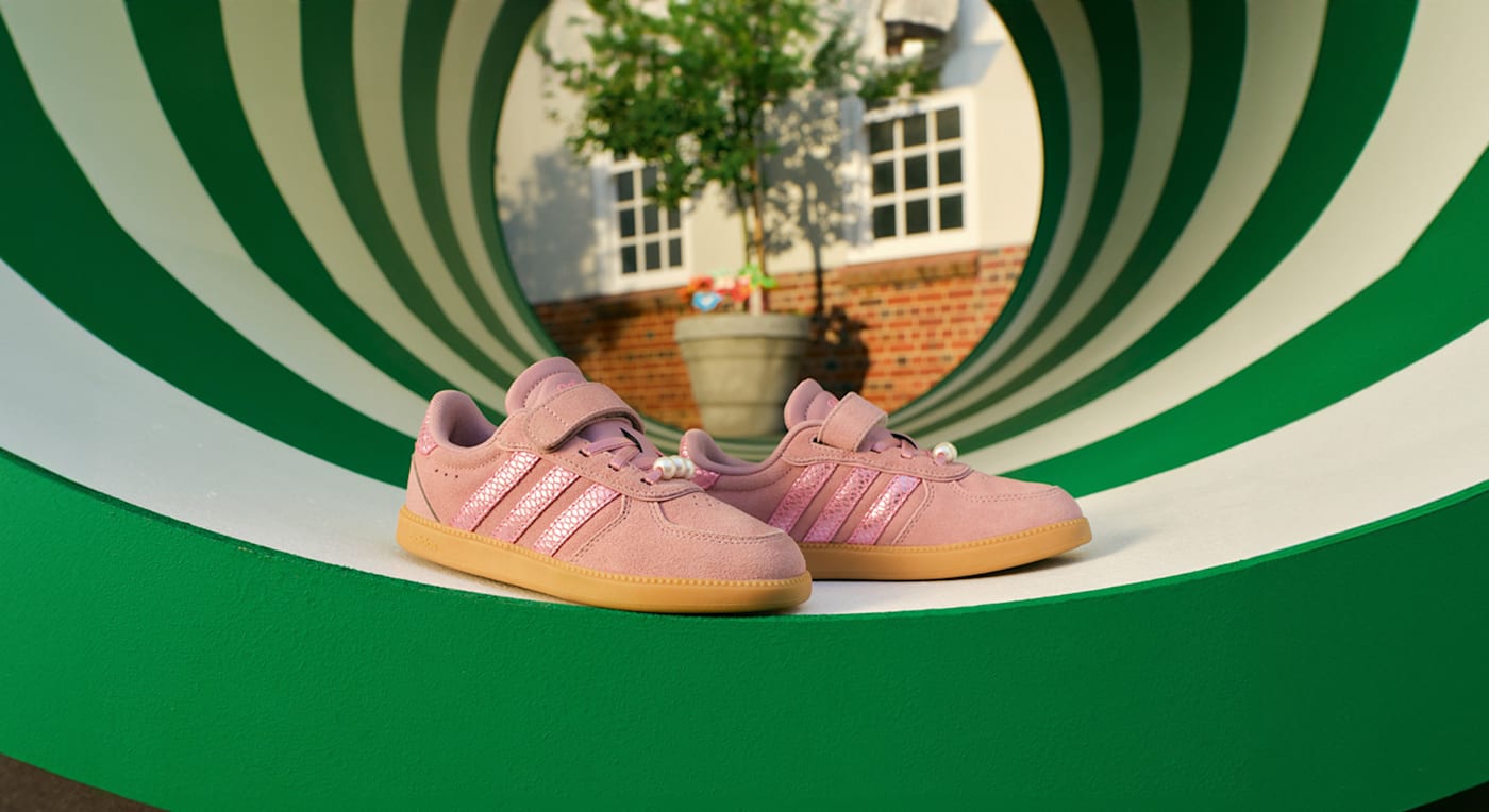 Sneaker Adidas rosa con effetto pelle scamosciata e suola in gomma, in uno scenario circolare da palestra