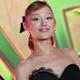 Sängerin Ariana Grande in schwarzem Kleid vor Graffiti-Fassade