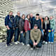 Gruppenfoto mit zehn Personen vor einer spiegelnden Gebäudefassade