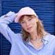 Blonde Frau in blauer Bluse mit rosa Cap auf dem Kopf