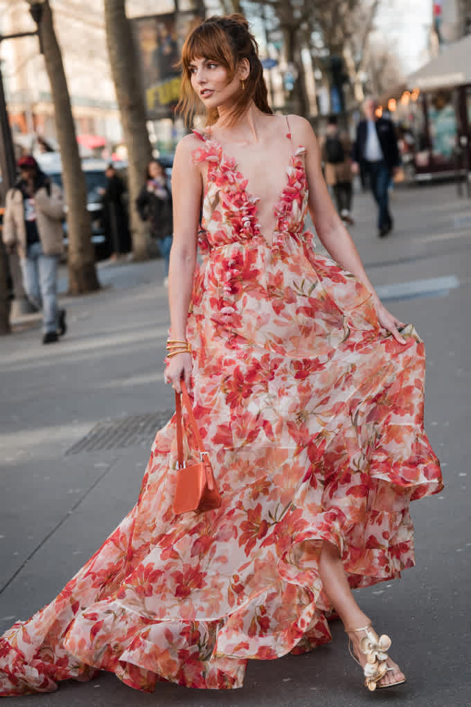 Frau in Floral Outfit, gekleidet in ein leichtes und wallendes rosa Blumenkleid mit Rüschen