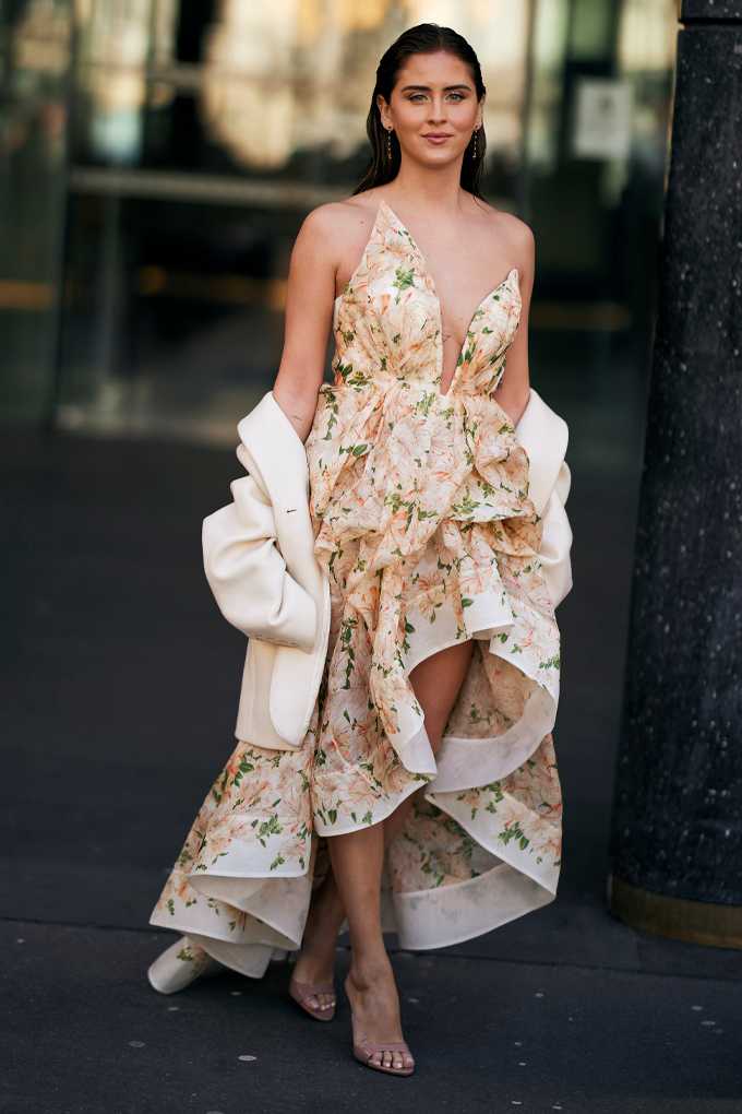 Frau in klassisch-floralem Kleid mit eleganter Silhouette, kombiniert mit edlen Pumps