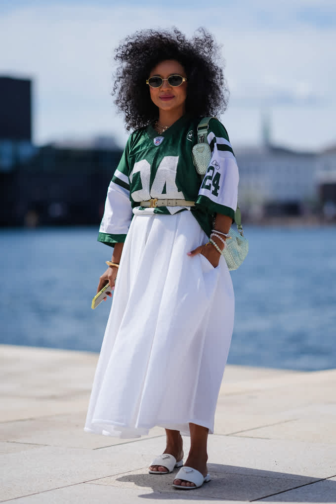 Frau mit grün-weißem Basketball-Trikot, kombiniert mit einem wallend-weißen langen Rock und Sneakern