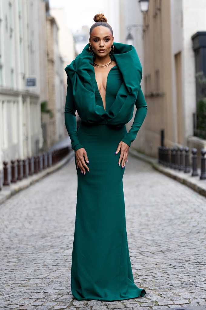 Eine Frau trägt ein ausgefallenes dunkelgrünes Kleid, das ihren natürlichen Teint unterstreicht 