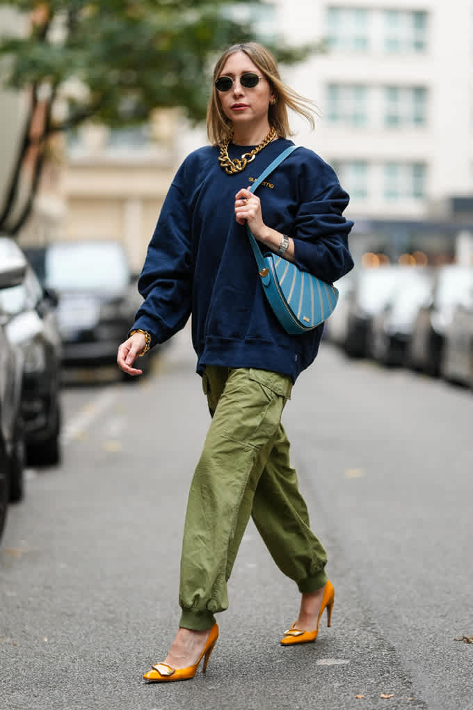 Eine Frau mit Mischtyp-Outfit vereint in ihrem Look sowohl kühle Farbtöne als auch warme Elemente, mit einer blauen Tasche und orangefarbenen Schuhen