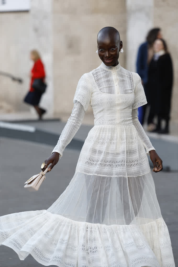 Frau mit dunkler Hautfarbe in perlweißem, transparentem Kleid