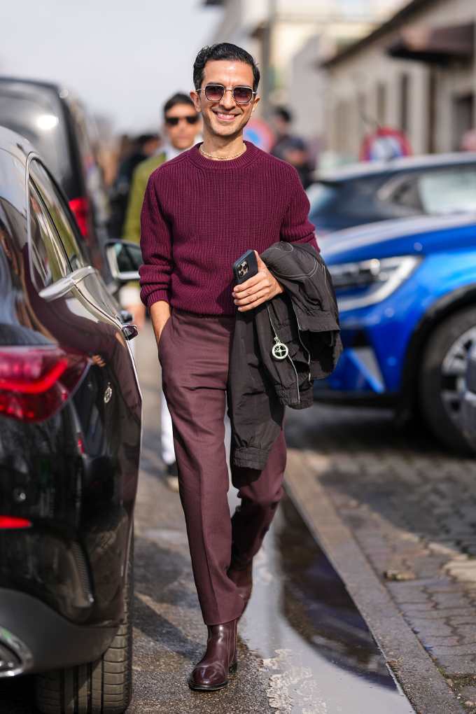 Mann in burgunderrotem Outfit mit Anzughose und Strickpullover