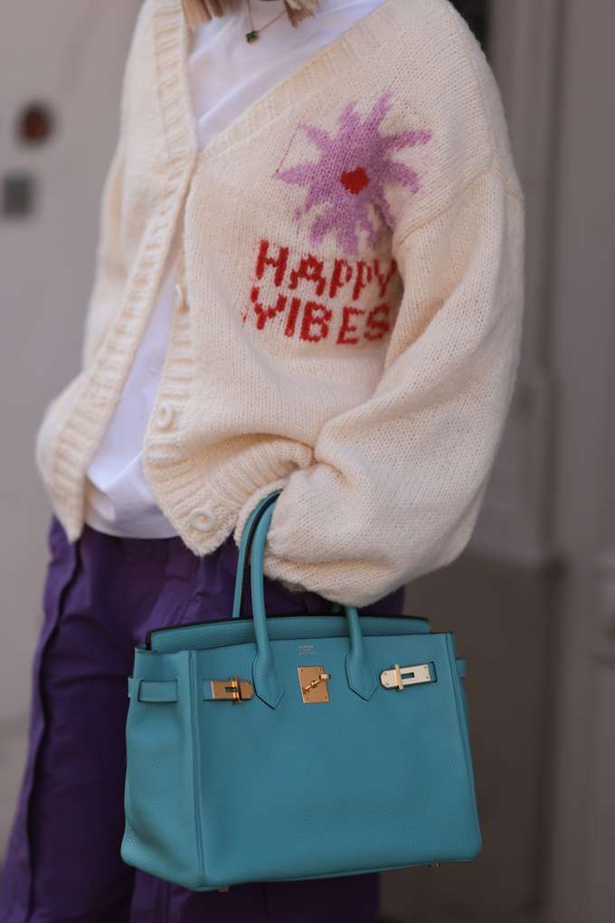 Frau in weißem Strick-Cardigan mit "Good Vibes"-Bestickung