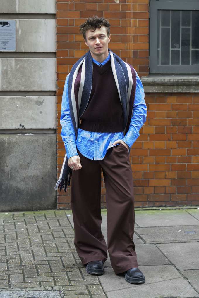 Mann mit schwarzem V-Neck-Pullunder aus Strick über blauem Hemd