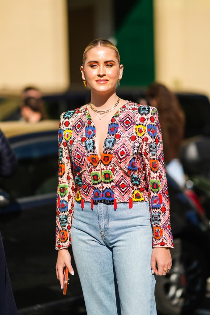 Junge Frau trägt bunte Ikat-Bluse, kombiniert mit High-Waist-Denim-Hose