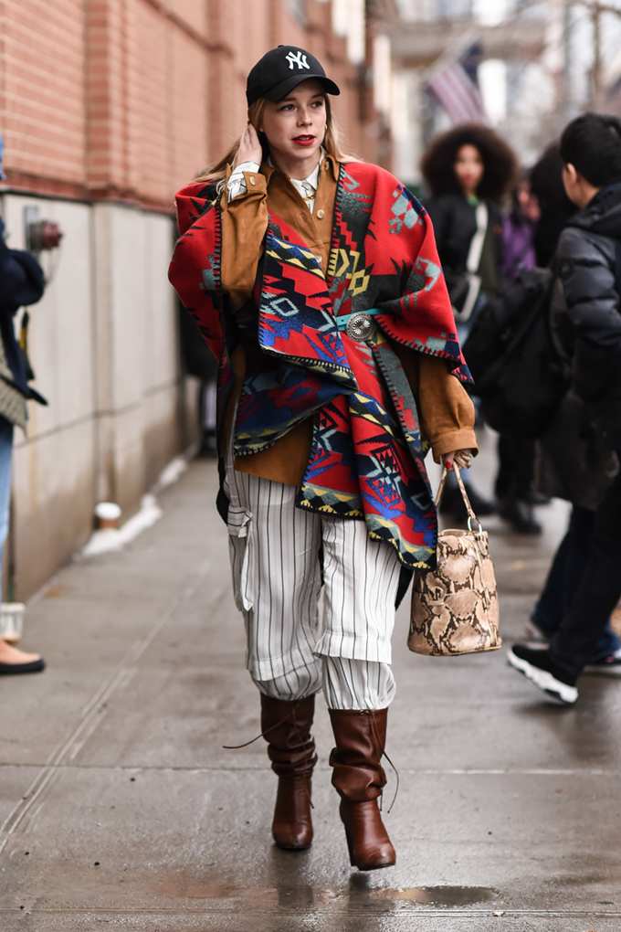Frau trägt bunten Ikat-Poncho kombiniert mit Streetstyle-Outfit