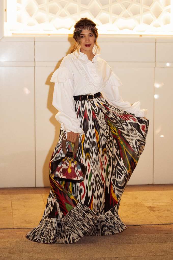 Frau mit weißem Top, kombiniert mit weitem Ikat-Rock und passender Handtasche