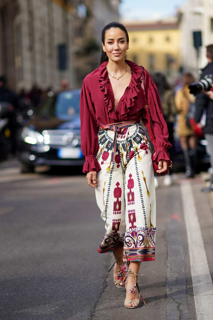 Frau mit roter Bluse und bunt gewebter Ikat-Hose, in urbaner Umgebung