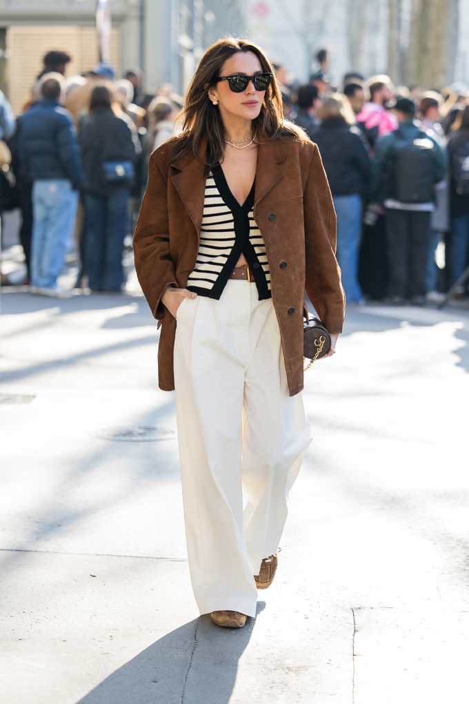 Frau mit braunem Wildleder-Blouson und weißer Hose für den French Chic