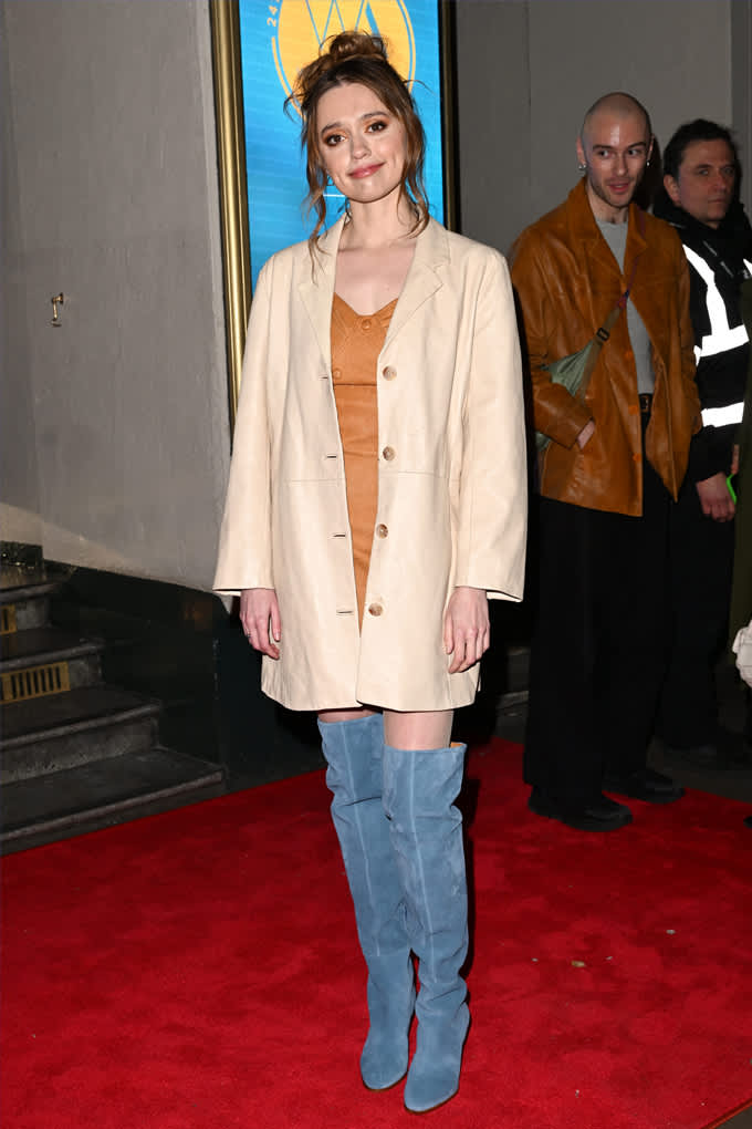 Schauspielerin Aimee Lou Wood kombiniert cremefarbenen Oversoze-Blazer mit blauen Overknees, steht auf rotem Teppich