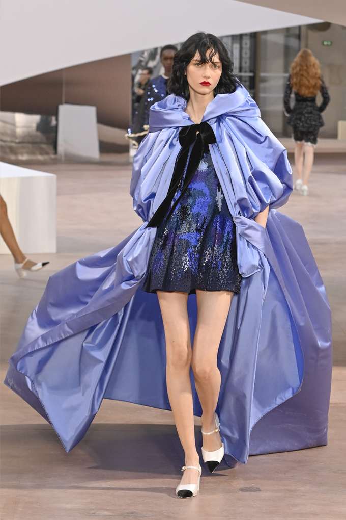 Schwarzhaarige Frau in wallendem Haute Couture-Kleid in blau-lila Farbton