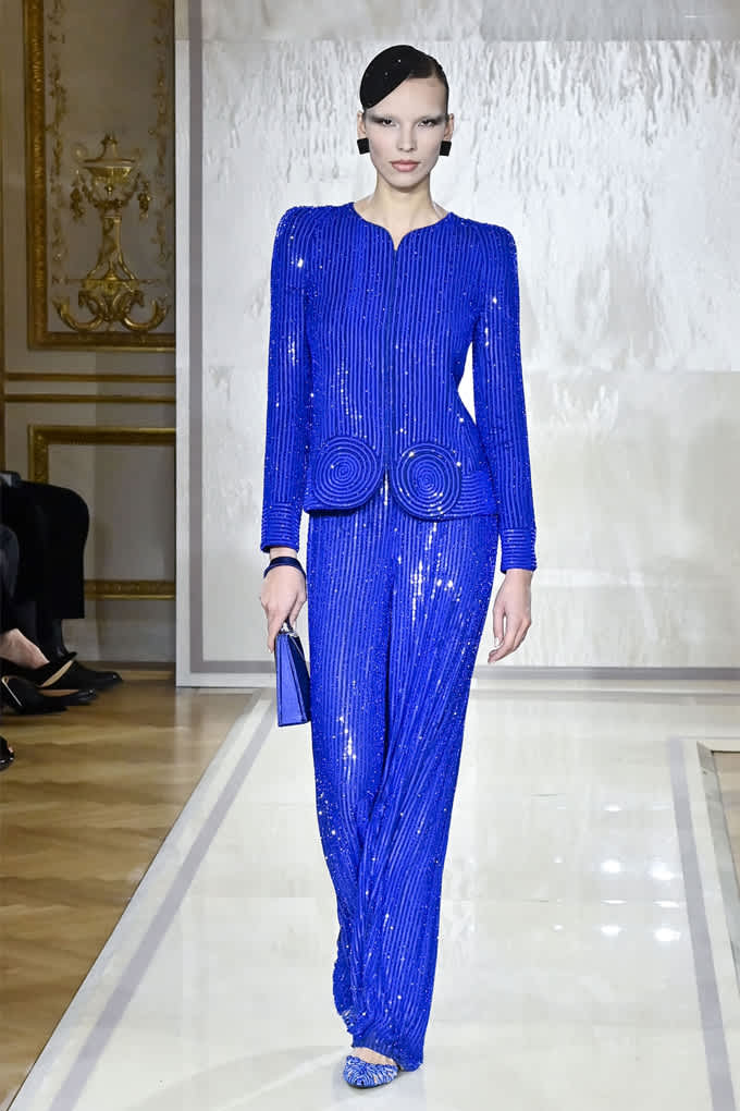 Frau in tiefblauem Outfit aus Hose und Blazer in schimmernder Optik