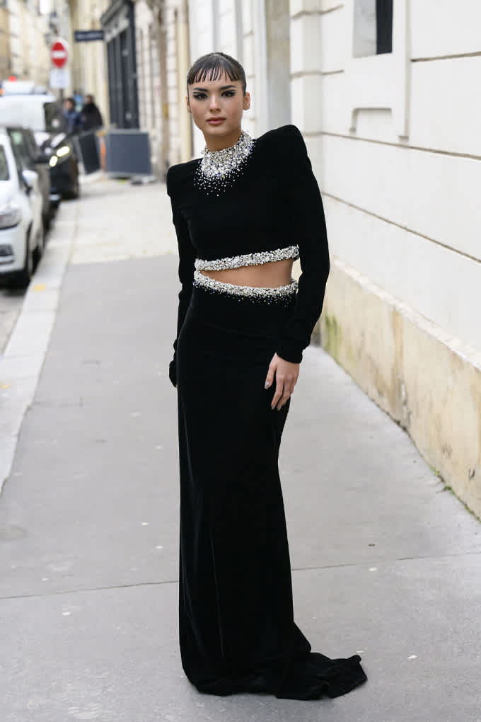 Frau in elegantem Zweiteiler-Outfit in Schwarz, langer Rock und Oberteil an den Nähten mit Diamanten besetzt
