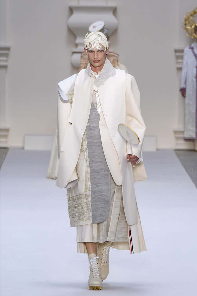 Frau auf Laufsteg, trägt extravagantes Layering-Outfit in reinem Weiß