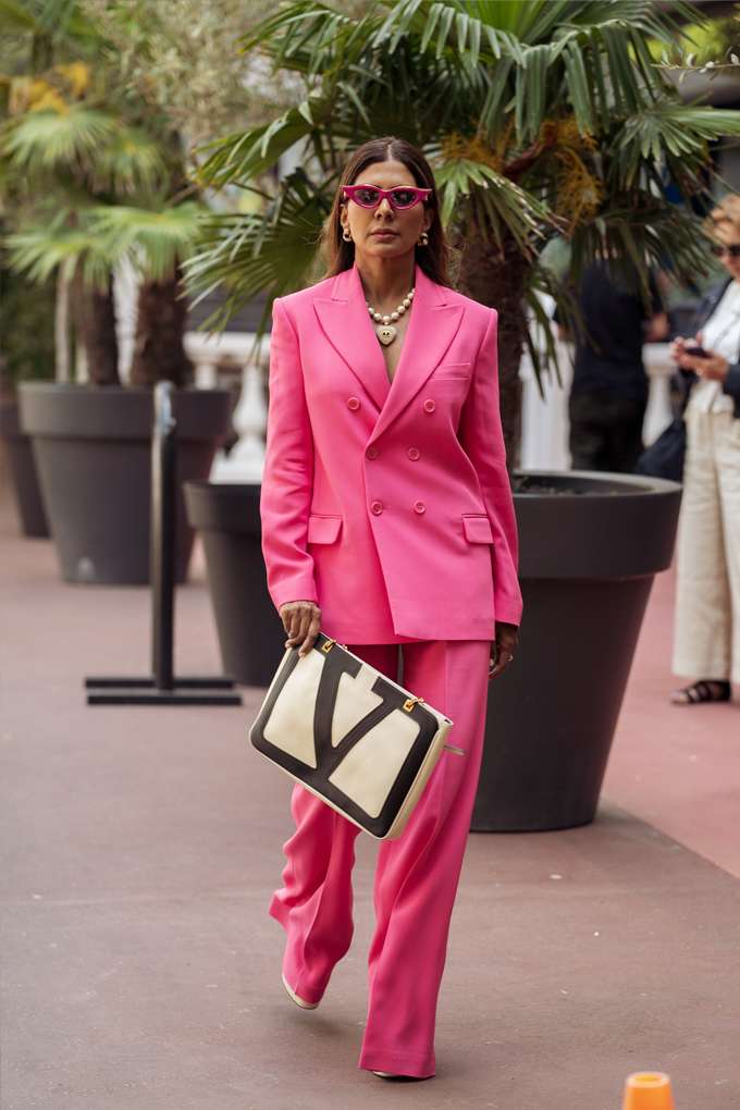Donna con blazer rosa e pantaloni abbinati, con una borsetta