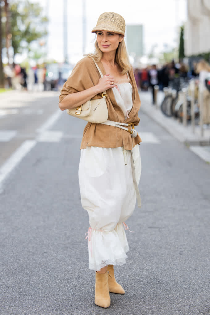 Donna con cappello di paglia, giacca in pelle scamosciata e stivaletti, abbinati per un look da spiaggia fresco