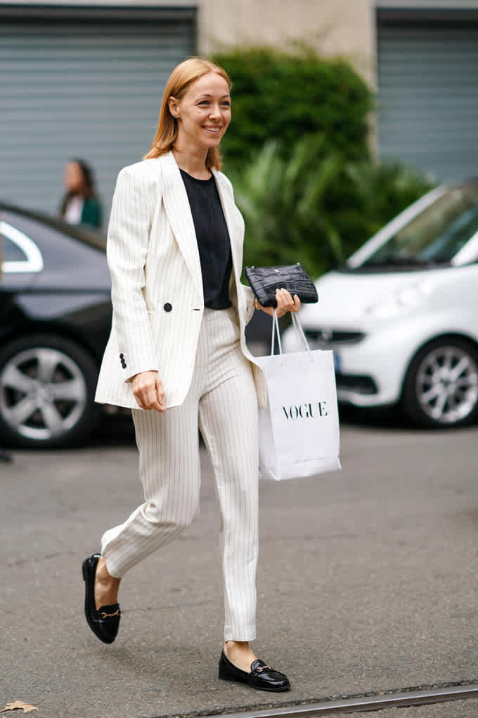 Donna con tailleur gessato bianco, camicia nera e mocassini