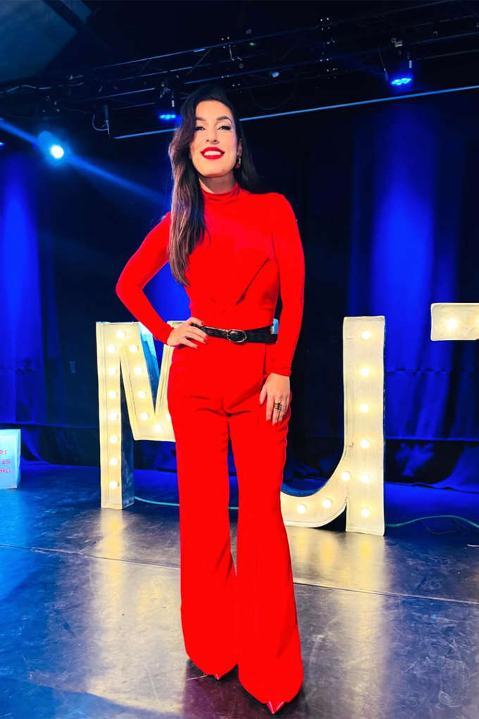 Tijen Onaran steht in rotem Ton-in-Ton-Outfit an einem Set
