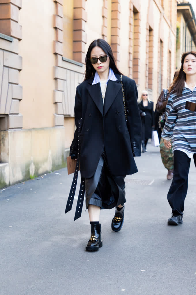 Junge Frau in Oversize-Blazer mit klobigen schwarzen Boots in Lack-Optik