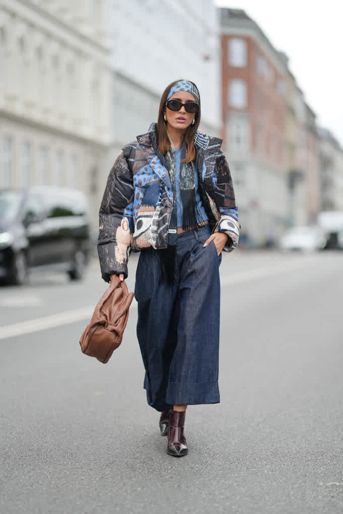 Frau in Patchwork-Denim-Jacke mit Wide-Leg-Jeans und brauner Handtasche