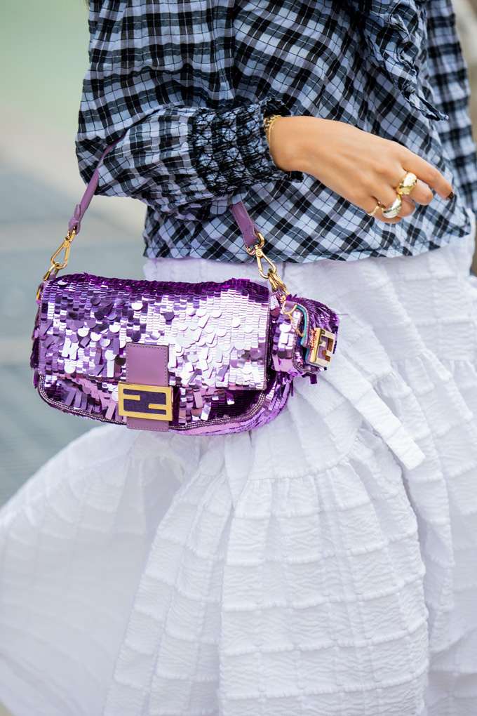 Frau trägt Fendi-Baguette Bag in Pailletten-Lila-Farbton am Arm