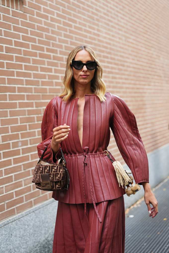 Blonde Frau in bordeauxrotem Outfit trägt farblich passende Baguette Bag