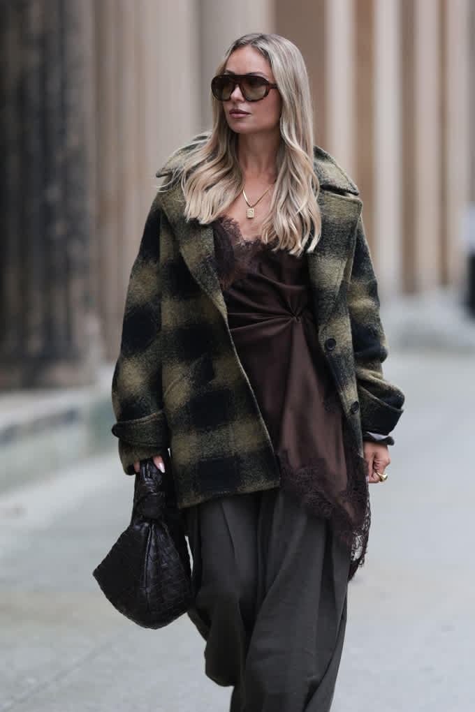 Blonde Frau mit dunkelgrüner Jacke, spaziert auf Gehweg