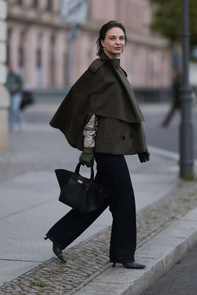 Frau in schwarzem Outfit, mit Blazer und eleganter Handtasche, im Heritage Style