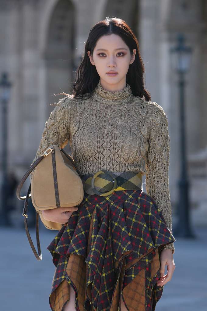 Frau in beigem Pullover, mit brauner Handtasche und Tuch am Bauch