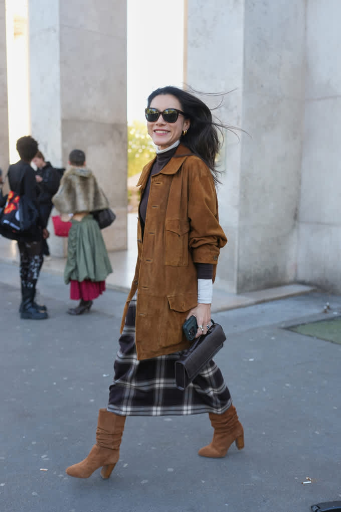 Frau trägt langen Karo-Rock im Heritage Style, kombiniert mit brauner Wildlederjacke und passenden Boots