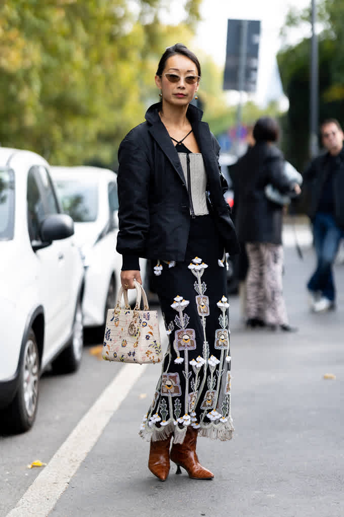 Frau trägt schwarze Jacke mit besticktem Maxi-Rock und Cowboy Boots