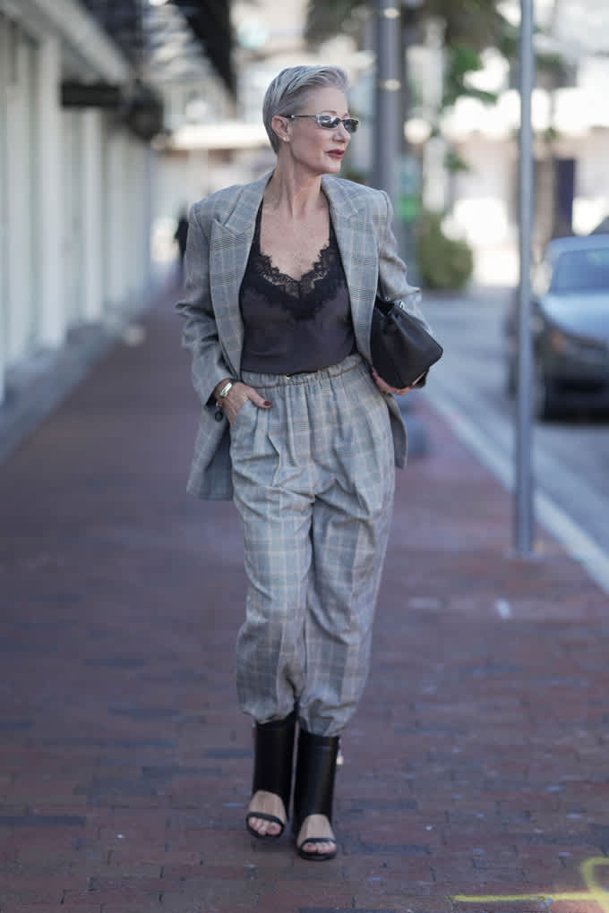 Frau in schwarzem Satin-Top mit grauem Karo-Suit