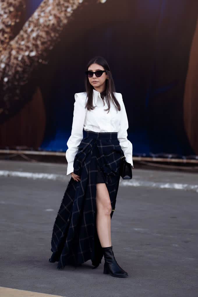 Frau im Heritage Style-Outfit, trägt weiße Bluse mit asymmetrisch drapiertem Rock im Schottenkaro