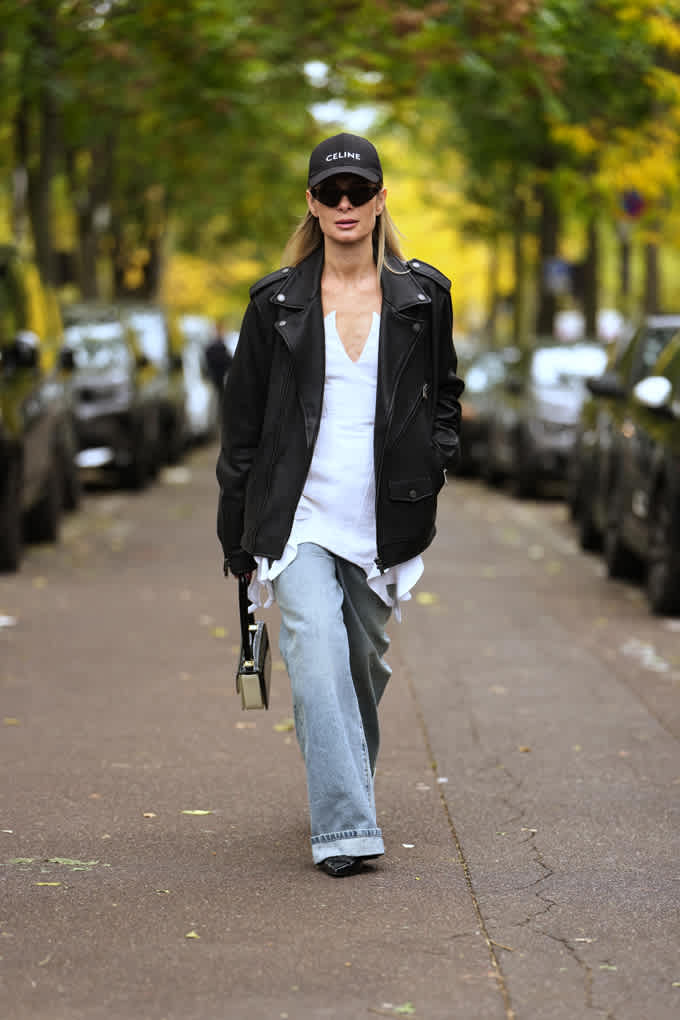 Frau trägt scjwarze Bikerjacke in Verbindung mit weißem Shirt und Jeanshose