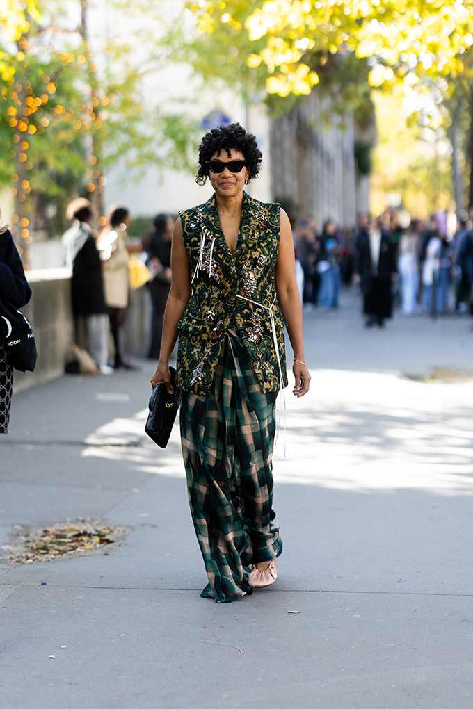 Junge Frau trägt grüne Jacquard-Weste mit farblich passemder Karo-Hose