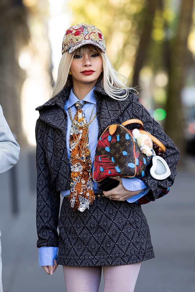 Junge Dame in Preppy-Street-Outfit mit Cap und Krawatte