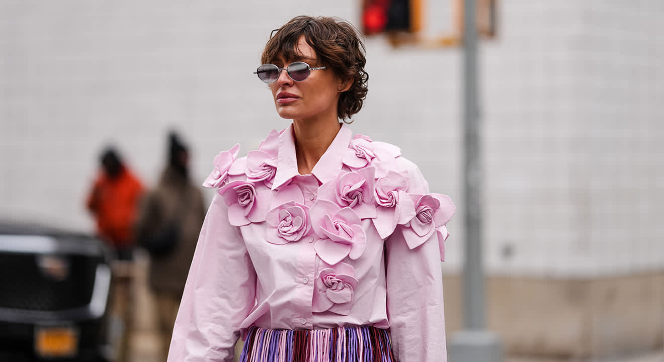 Frau in rosa Oberteil mit auffälligen Blumen-Applikationen