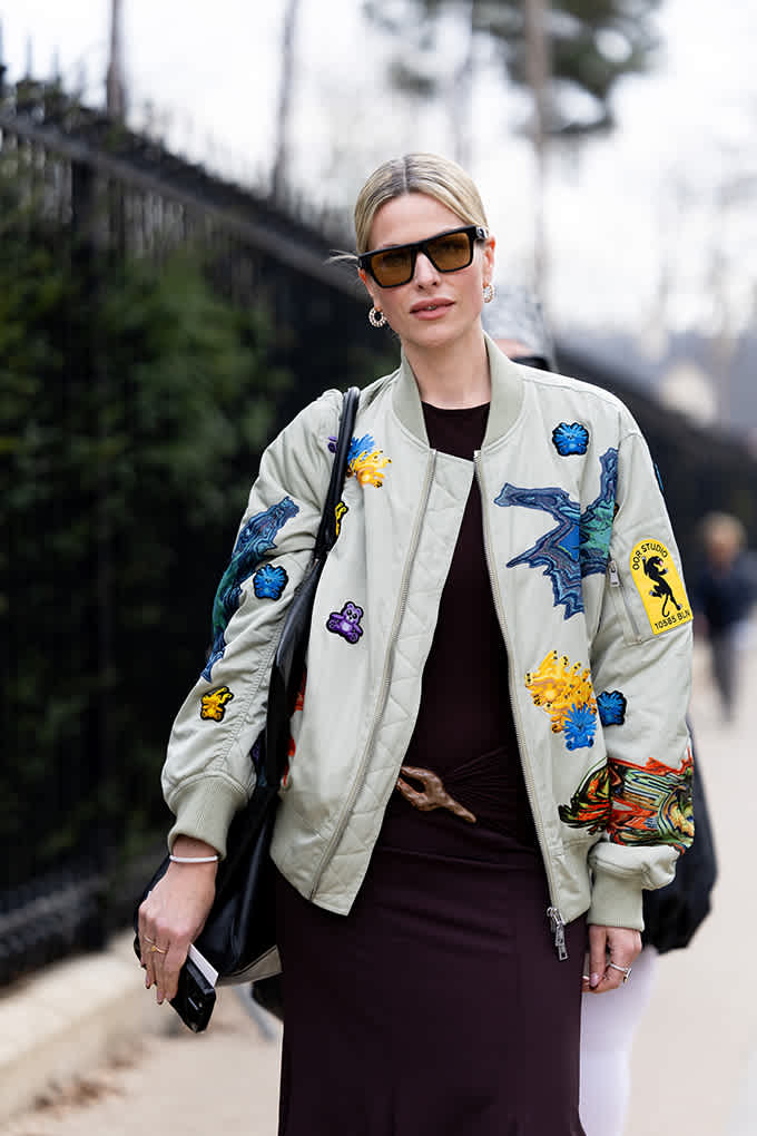 Frau mit Sonnenbrille trägt helle Bomberjacke mit Patch-Applikationen