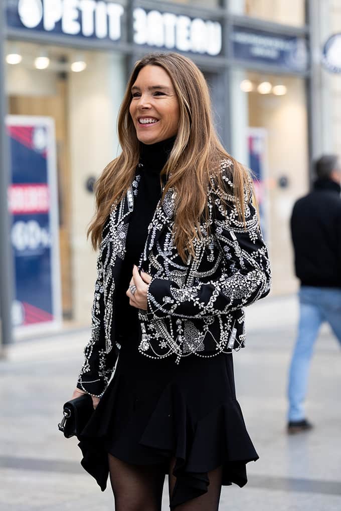 Junge Frau trägt schwarzen Dress unter kurzer Jacke mit eleganten Applikationen