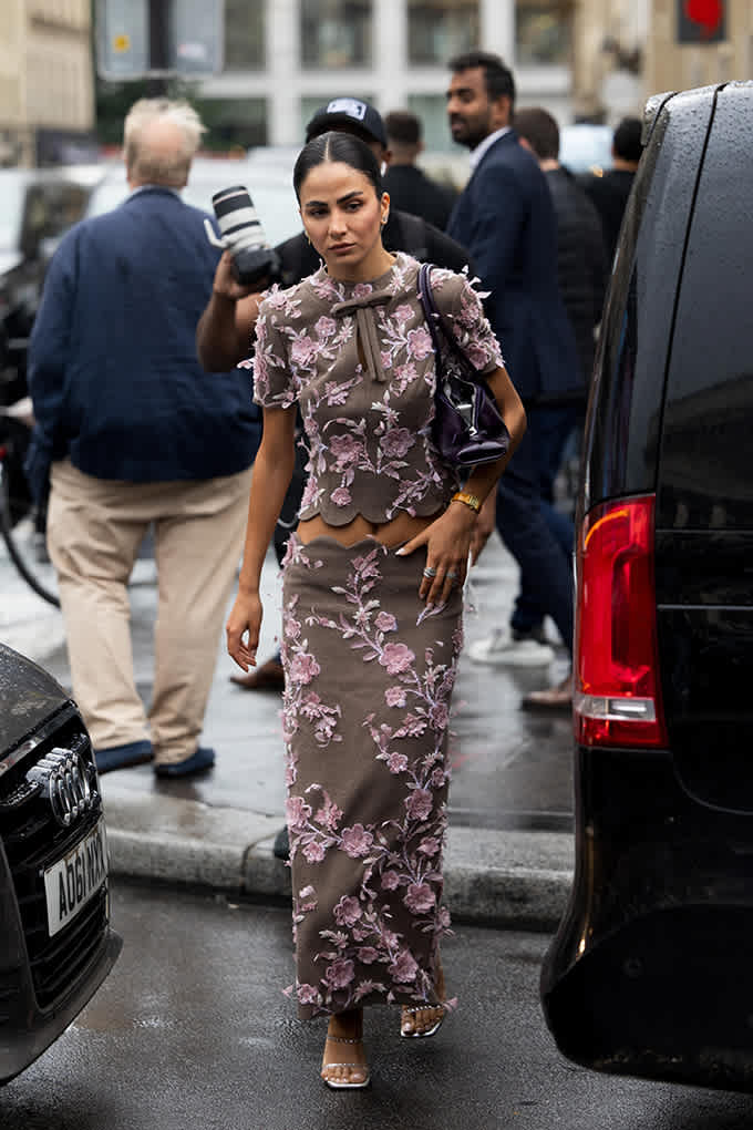 Frau spaziert in taupefarbenem Zweiteiler über die Straße